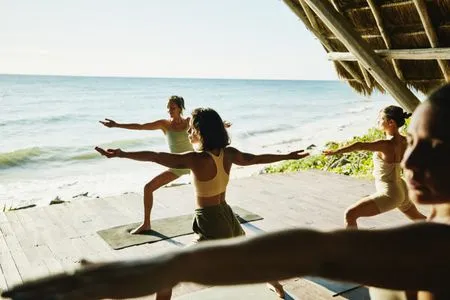   קבוצת נשים עושות יוגה בשיעור חיצוני בספא של מלון על החוף ליד האוקיינוס.