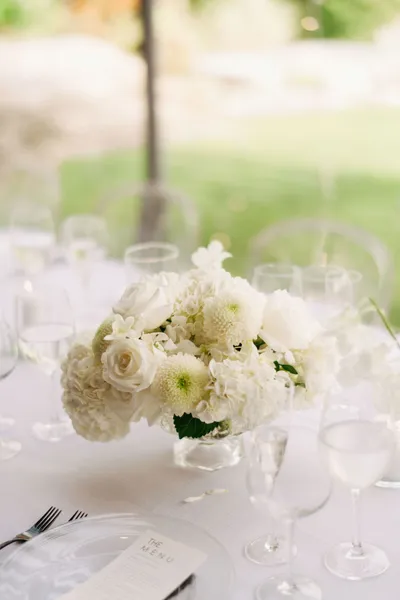   ג'ולי ומיגל's white floral centerpieces with hydrangea, roses, and ranunculus