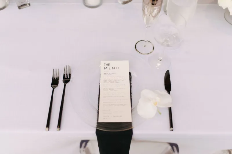   Julie i Miguel's places set with lucite chargers, black napkins, and black flatware