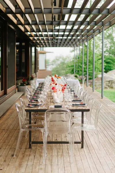   Julie i Miguel's tea ceremony reception on the deck with ghost chairs and a wooden banquet table