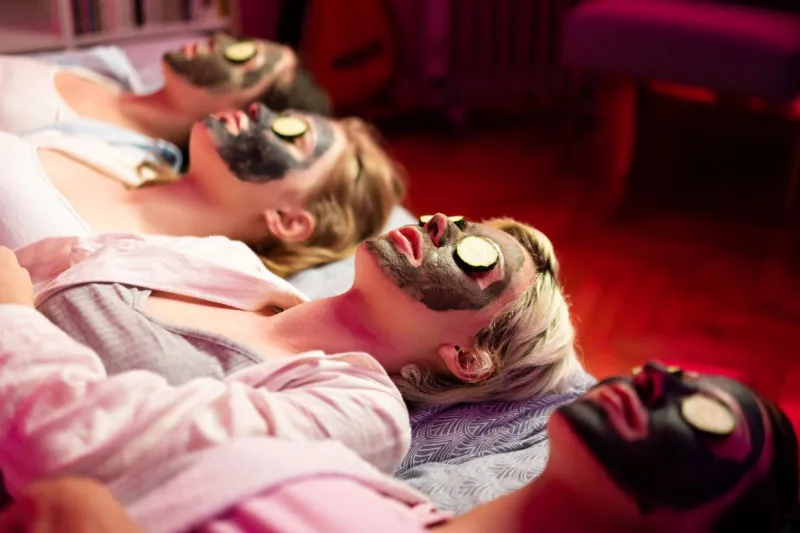   Neljä naista makasi naamarit ja kurkut silmissä pyjamajuhlissa.