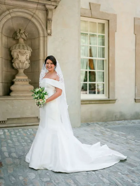   Sarah's off-the-shoulder dress and bouquet of white flowers and greenery