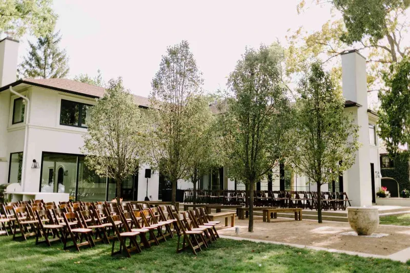   Alex e Uche's outdoor ceremony with wooden folding chairs and benches