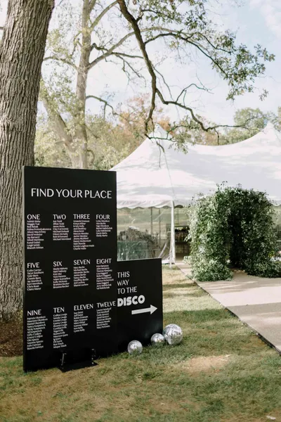   Alex e Uche's black minimalist seating chart and disco sign