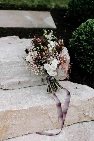   Alex's moody bouquet of roses, baby's breath, and grasses wrapped in a ribbon