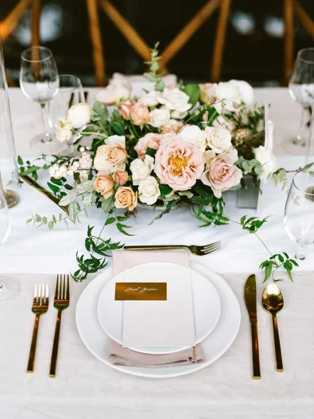   Grace i JP's places set with gold flatware, white chargers, gold place cards, and pink napkins
