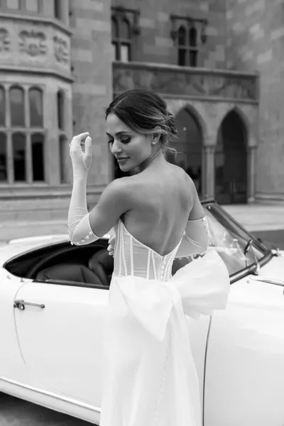   Olivia Amato osvrće se u svojoj vjenčanici s mašnom i automobilom iza sebe