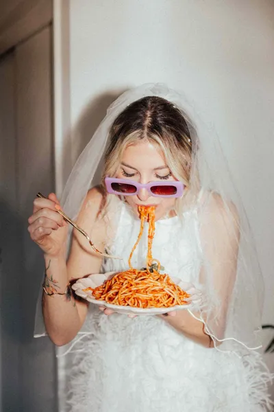   mladenka s ljubičastim sunčanim naočalama jede tanjur špageta