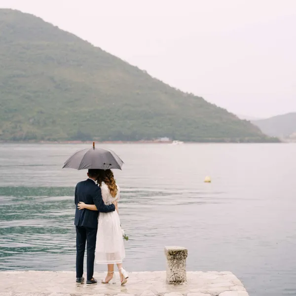   Par under paraplyet tittar på en sjö