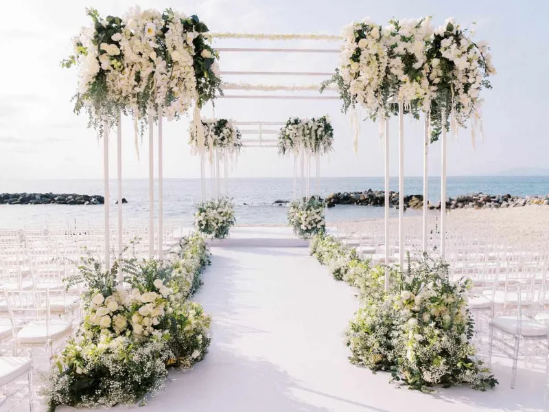   Brittani ja Jared's aisle lined with white flowers and greenery and several arches