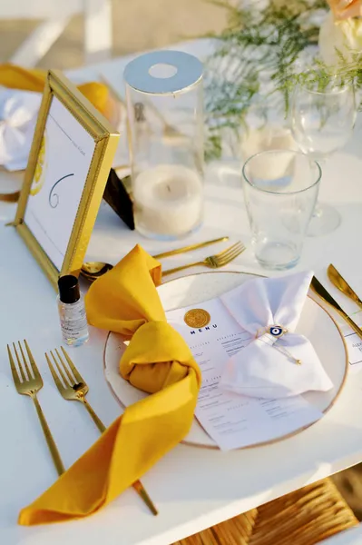   Christina ja Leo's place settings with gold-rimmed chargers, marigolds napkins, and gold flatware