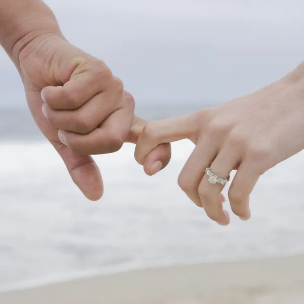   Dua tangan saling berhubungan dengan cincin pertunangan berlian dipajang
