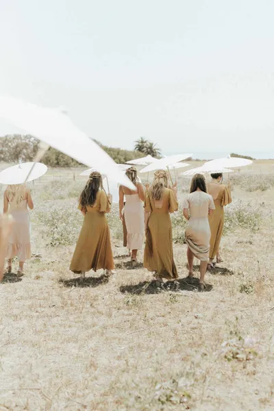   Kenzie's bridesmaids wearing gold and champagne dresses and carrying parasols